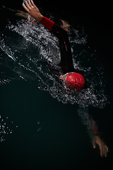 Image showing A determined professional triathlete undergoes rigorous night time training in cold waters, showcasing dedication and resilience in preparation for an upcoming triathlon swim competition