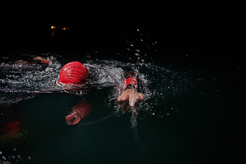 Image showing A determined professional triathlete undergoes rigorous night time training in cold waters, showcasing dedication and resilience in preparation for an upcoming triathlon swim competition