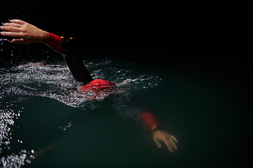 Image showing A determined professional triathlete undergoes rigorous night time training in cold waters, showcasing dedication and resilience in preparation for an upcoming triathlon swim competition