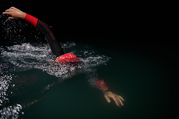 Image showing A determined professional triathlete undergoes rigorous night time training in cold waters, showcasing dedication and resilience in preparation for an upcoming triathlon swim competition