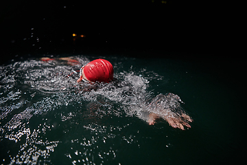 Image showing A determined professional triathlete undergoes rigorous night time training in cold waters, showcasing dedication and resilience in preparation for an upcoming triathlon swim competition