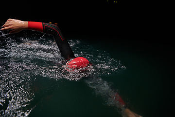 Image showing A determined professional triathlete undergoes rigorous night time training in cold waters, showcasing dedication and resilience in preparation for an upcoming triathlon swim competition