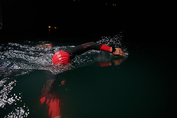 Image showing A determined professional triathlete undergoes rigorous night time training in cold waters, showcasing dedication and resilience in preparation for an upcoming triathlon swim competition