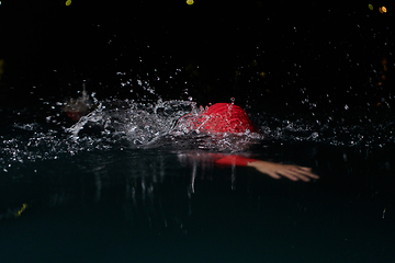 Image showing A determined professional triathlete undergoes rigorous night time training in cold waters, showcasing dedication and resilience in preparation for an upcoming triathlon swim competition