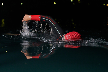 Image showing A determined professional triathlete undergoes rigorous night time training in cold waters, showcasing dedication and resilience in preparation for an upcoming triathlon swim competition