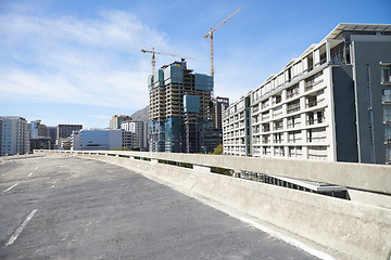 Image showing City, road and CBD of Cape Town construction, industrial architecture or buildings in urban suburb. Asphalt street and concrete infrastructure with blue sky, cranes and empty bridge in South Africa