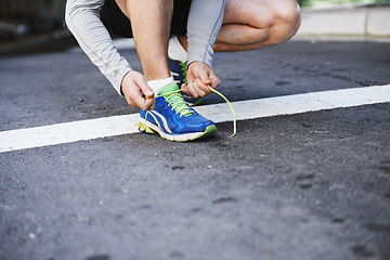 Image showing Foot, runner and tying laces on road in outdoors, cardio and exercise or training for marathon. Person, athlete and ready for workout in closeup, sportswear and performance challenge on asphalt