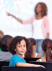 Image showing Portrait, boy child or student in classroom for knowledge, education or development for future growth. School, teacher blur or back of a clever kid with book or pride for studying or learning at desk