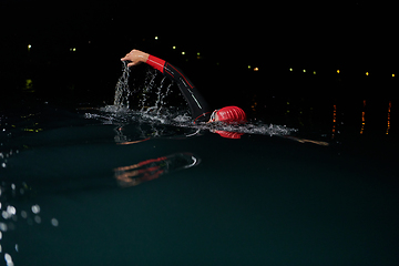 Image showing A determined professional triathlete undergoes rigorous night time training in cold waters, showcasing dedication and resilience in preparation for an upcoming triathlon swim competition