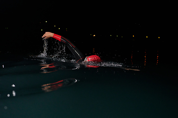 Image showing A determined professional triathlete undergoes rigorous night time training in cold waters, showcasing dedication and resilience in preparation for an upcoming triathlon swim competition