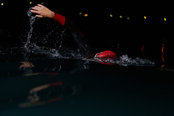 Image showing A determined professional triathlete undergoes rigorous night time training in cold waters, showcasing dedication and resilience in preparation for an upcoming triathlon swim competition