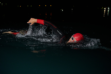 Image showing A determined professional triathlete undergoes rigorous night time training in cold waters, showcasing dedication and resilience in preparation for an upcoming triathlon swim competition