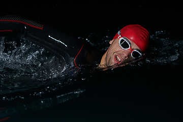 Image showing A determined professional triathlete undergoes rigorous night time training in cold waters, showcasing dedication and resilience in preparation for an upcoming triathlon swim competition