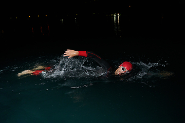 Image showing A determined professional triathlete undergoes rigorous night time training in cold waters, showcasing dedication and resilience in preparation for an upcoming triathlon swim competition