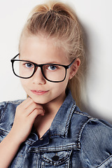 Image showing Child, portrait and fashion glasses in studio, cool and confidence by white background. Female person, girl and casual clothing or style by backdrop, kid and denim jacket pride for eyesight test