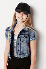 Image showing Child, portrait and fashion in studio, cool and confidence by white background. Female person, girl and casual clothing or style by backdrop, kid and denim jacket pride or smiling for trendy cap