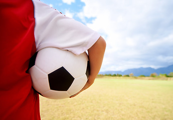 Image showing Child, arm and soccer ball on green grass for sports, training or practice in cloudy blue sky. Closeup of football player, athlete or kid ready for kick off, game or match on outdoor field in nature