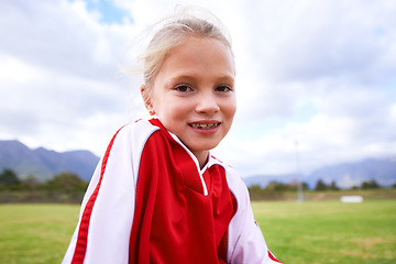 Image showing Happy girl, portrait and soccer on green grass for sports, training or practice with clouds and blue sky. Face of female person or football player smile for game or match on outdoor field in nature