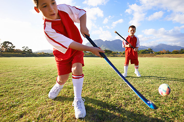 Image showing Children, ball and playing hockey on green grass for game, sports or outdoor match together. Team, kids or players enjoying day on field for fitness, activity or practice in nature with blue sky