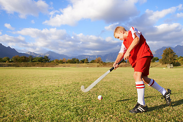 Image showing Child, ball and hockey on field for sports, outdoor practice match or game in nature. Young kid or teen player enjoying day on green grass with stick for fitness, activity or training with blue sky