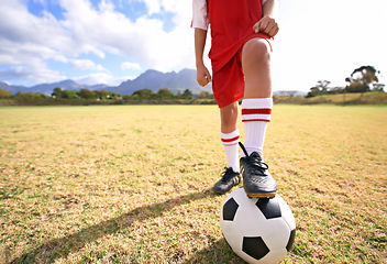 Image showing Child, soccer ball and legs on green field for sports, training or practice with clouds and blue sky. Closeup of football player with foot ready for kick off, game or match on outdoor grass in nature