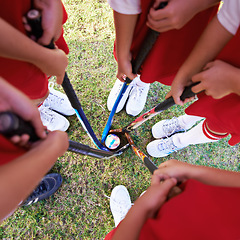 Image showing Children, hockey team and huddle above with ball on green grass for sports, match or game together. Top view closeup of kids, player hands and sticks on field for teamwork or outdoor unity in nature