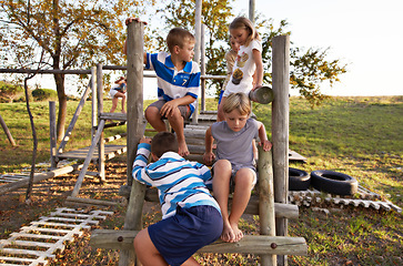 Image showing Children, friends and playing at park together on jungle gym for fun weekend, holiday or summer break in nature. Group of young kids or teens enjoying day at outdoor playground for game or activity