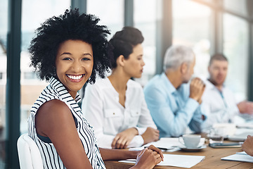 Image showing Shes an invaluable member of the team. Portrait of a smiling businesswoman sitting in a boardroom with colleagues in the background.