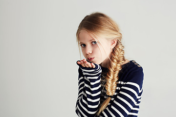 Image showing Fashion, kiss and portrait of child in a studio with casual, cool and stylish outfit and hat. Happy, youth and young girl kid with positive, good and confident attitude for style by white background