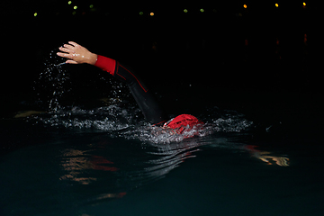 Image showing A determined professional triathlete undergoes rigorous night time training in cold waters, showcasing dedication and resilience in preparation for an upcoming triathlon swim competition