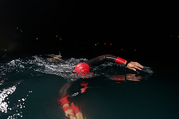 Image showing A determined professional triathlete undergoes rigorous night time training in cold waters, showcasing dedication and resilience in preparation for an upcoming triathlon swim competition