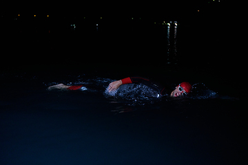 Image showing A determined professional triathlete undergoes rigorous night time training in cold waters, showcasing dedication and resilience in preparation for an upcoming triathlon swim competition