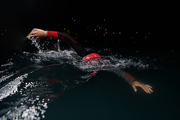 Image showing A determined professional triathlete undergoes rigorous night time training in cold waters, showcasing dedication and resilience in preparation for an upcoming triathlon swim competition