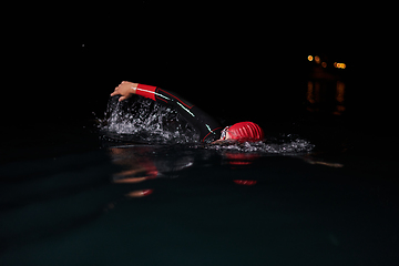 Image showing A determined professional triathlete undergoes rigorous night time training in cold waters, showcasing dedication and resilience in preparation for an upcoming triathlon swim competition