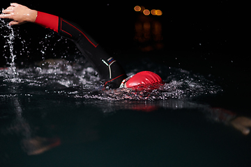 Image showing A determined professional triathlete undergoes rigorous night time training in cold waters, showcasing dedication and resilience in preparation for an upcoming triathlon swim competition