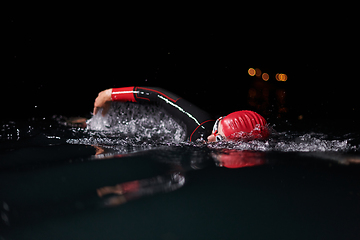 Image showing A determined professional triathlete undergoes rigorous night time training in cold waters, showcasing dedication and resilience in preparation for an upcoming triathlon swim competition