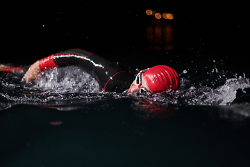 Image showing A determined professional triathlete undergoes rigorous night time training in cold waters, showcasing dedication and resilience in preparation for an upcoming triathlon swim competition