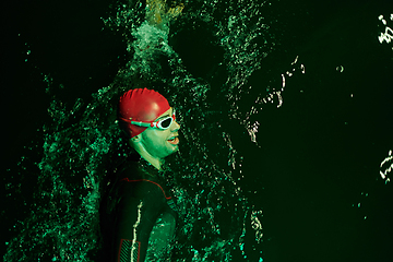 Image showing Authentic triathlete swimmer having a break during hard training on night neon gel light