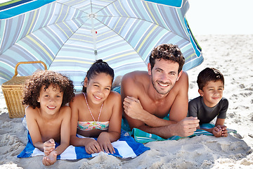 Image showing Happy family, portrait and beach umbrella for bonding, vacation or outdoor holiday weekend together. Father, mother and children smile lying on sand for love, support or summer break by ocean or sea