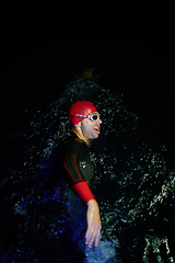 Image showing Authentic triathlete swimmer having a break during hard training on night neon gel light