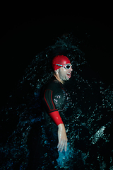 Image showing Authentic triathlete swimmer having a break during hard training on night neon gel light