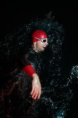 Image showing Authentic triathlete swimmer having a break during hard training on night neon gel light