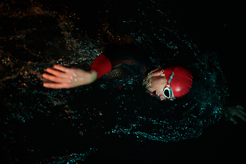 Image showing A determined professional triathlete undergoes rigorous night time training in cold waters, showcasing dedication and resilience in preparation for an upcoming triathlon swim competition