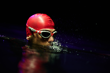 Image showing A determined professional triathlete undergoes rigorous night time training in cold waters, showcasing dedication and resilience in preparation for an upcoming triathlon swim competition