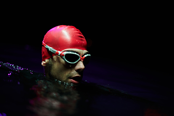 Image showing A determined professional triathlete undergoes rigorous night time training in cold waters, showcasing dedication and resilience in preparation for an upcoming triathlon swim competition