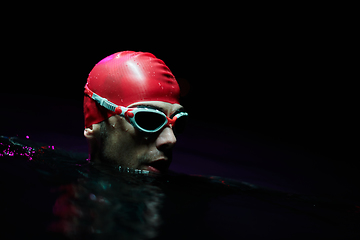 Image showing A determined professional triathlete undergoes rigorous night time training in cold waters, showcasing dedication and resilience in preparation for an upcoming triathlon swim competition