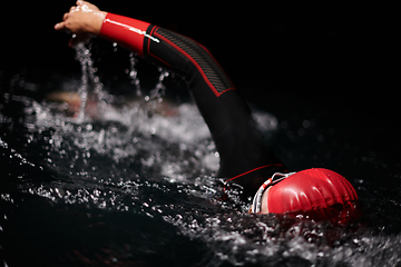 Image showing A determined professional triathlete undergoes rigorous night time training in cold waters, showcasing dedication and resilience in preparation for an upcoming triathlon swim competition