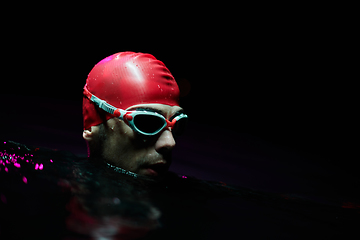 Image showing A determined professional triathlete undergoes rigorous night time training in cold waters, showcasing dedication and resilience in preparation for an upcoming triathlon swim competition