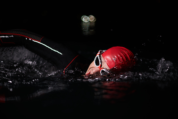 Image showing A determined professional triathlete undergoes rigorous night time training in cold waters, showcasing dedication and resilience in preparation for an upcoming triathlon swim competition