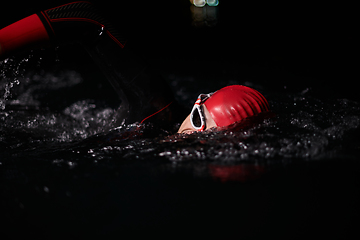 Image showing A determined professional triathlete undergoes rigorous night time training in cold waters, showcasing dedication and resilience in preparation for an upcoming triathlon swim competition